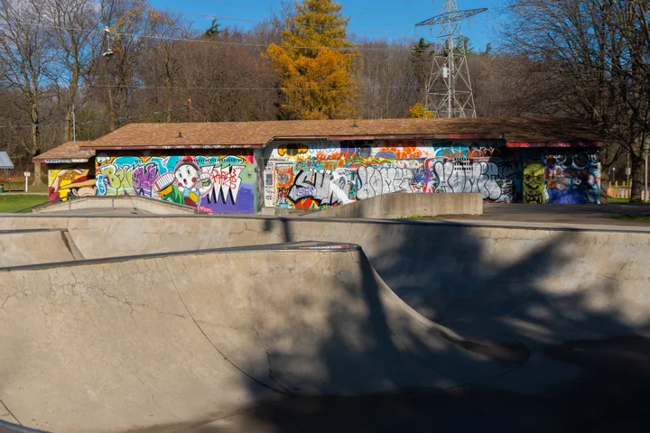 Concrete skateboard features and mural-covered building at Riverside Rails.